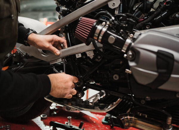 Repairman repair motorcycle, maintenance in garage. Mechanic fixing bike in a modern shop